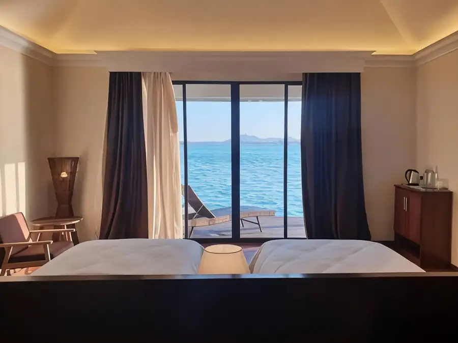 A cozy built-in bed inside a relaxing bedroom at Sea Star Resort near Bum Bum Island highlighting colorful pillows, a glowing leaf lamp, authentic glossy hardwood floors, and A/C.