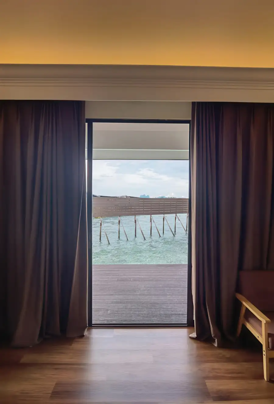 A tranquil bedroom at Sea Star Resort near Bum Bum Island featuring glass doors opening onto the private balcony with seaviews, smooth wooden floor planks, and A/C.