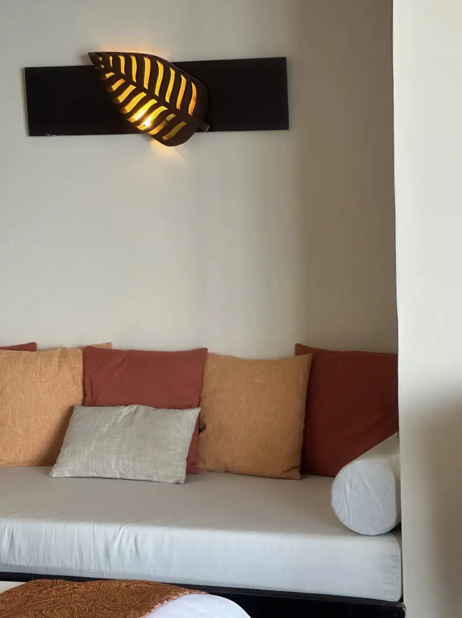 A relaxing bedroom at Sea Star Resort near Semporna highlighting a cozy daybed with colorful pillows, a decorative leaf lamp, modern decor, and AC.