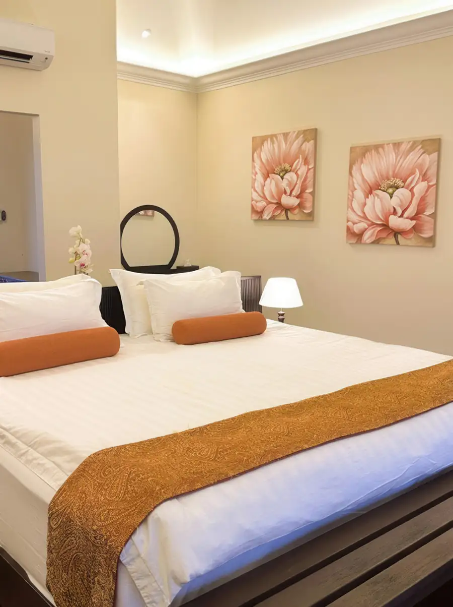 An inviting bed inside a cozy bedroom at Sea Star Resort near Semporna showcasing a comfortable built-in reading nook, yellow pillows, a decorative leaf wall lamp, and air conditioning.