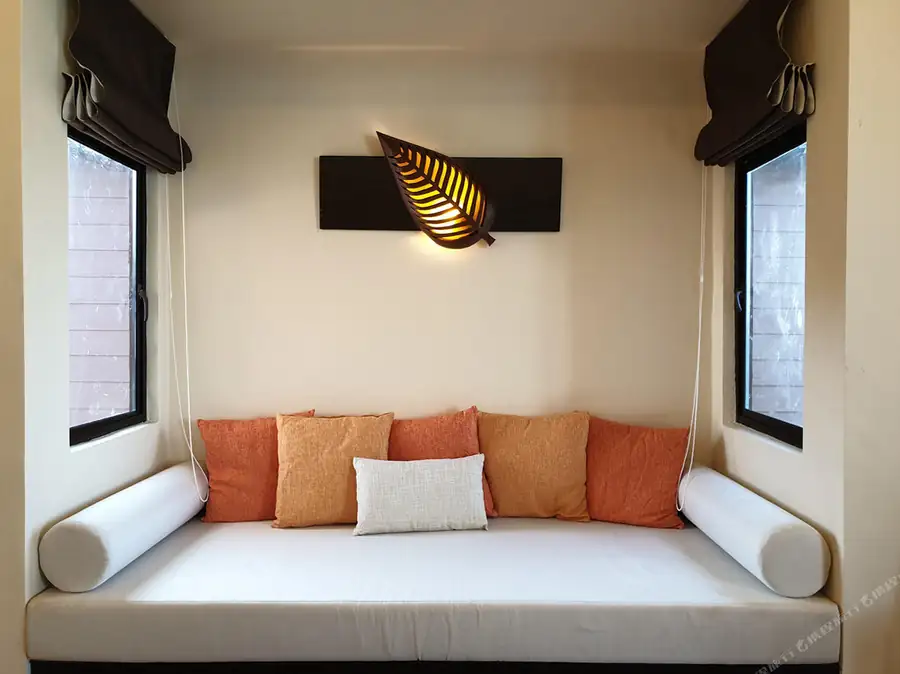 A comfortable bedroom at Sea Star Resort near Semporna focusing on a relaxing daybed reading nook, a decorative illuminated leaf lamp, modern seating, and air con.