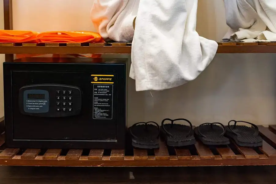 An open wooden shelving unit providing a digital safe, bathrobes, and slippers for guests, reflecting a traditional Sabah style at Sea Star Resort.